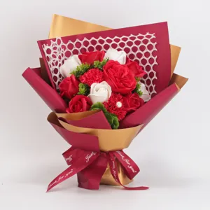 Detailed view of artificial rose soap flower bouquet wrapped in red and gold paper.
