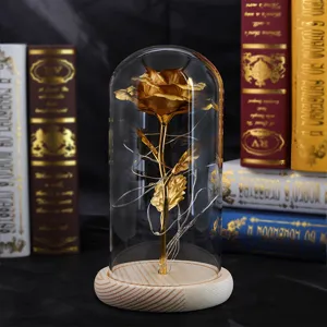 Detail einer goldenen künstlichen Rose in einer Glaskuppel mit LED-Lichterkette.