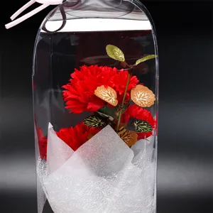 Vue détail d'un bouquet de fleurs artificielles d'œillets rouges en boîte transparente.