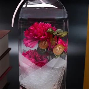 Vue détaillée du bouquet de fleurs d'œillets artificiels dans un emballage cadeau transparent.