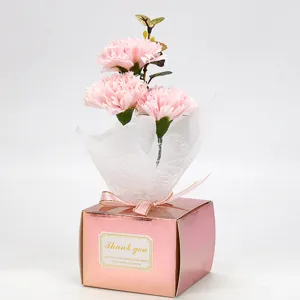 Gros plan d'un bouquet de carnations en savon rose dans une boîte cadeau métallique.