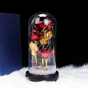 Detail view of three red foil roses in a clear glass dome with glowing LED fairy lights.