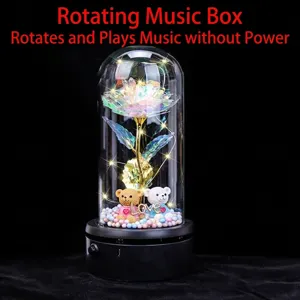 Close-up of rotating music box with colorful foil rose and cute bears in glass dome