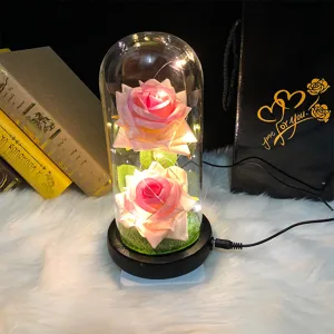 Primer plano de dos rosas rosas artificiales en cúpula de cristal con bolsa negra