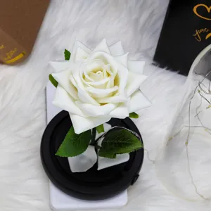 Primer plano detallado de una rosa de terciopelo blanco con luces LED sobre una base negra.