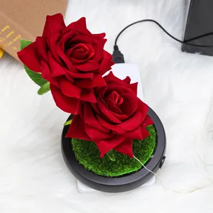 Detalle de dos rosas de terciopelo rojo con base USB sobre una alfombra blanca