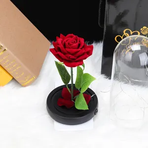 Detalle de rosa roja artificial de terciopelo con base negra y cúpula de cristal transparente