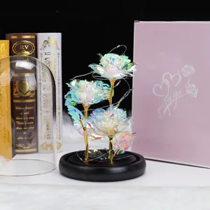 Detalle de rosa iridiscente en cúpula de cristal con luces LED y caja de regalo