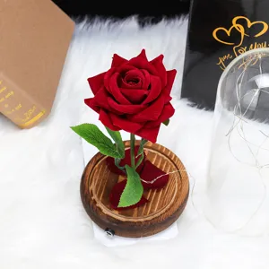 Detalle de una rosa de terciopelo rojo sobre base de madera con guirnaldas de luces LED