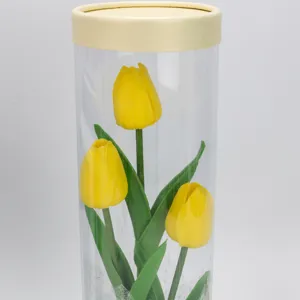 Transparent cylindrical box with three yellow artificial tulips for home decor and gifts.
