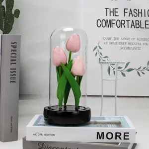 Détail de la veilleuse tulipe sous cloche en verre avec fleurs artificielles et socle noir.