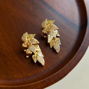 Primer plano de pendientes de hoja de oro vintage con cristales brillantes.