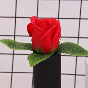 Close-up of a single red rose soap flower in a black decorative cylinder.