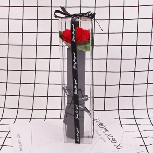 Close-up view of a single red soap rose in a transparent PVC gift box with black ribbon