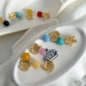 Primo piano di orecchini asimmetrici a conchiglia e stella marina con pietre colorate