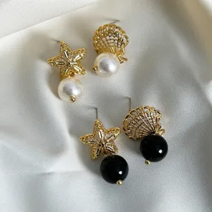 Dettaglio ravvicinato di eleganti orecchini asimmetrici d'oro con stella e perla