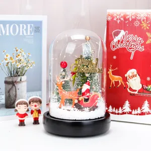 Primo piano di una cupola di vetro natalizia con luci a LED e figurine festive.