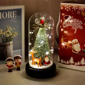 Dettaglio di una cupola di Natale festiva con luci LED, albero in miniatura e renna