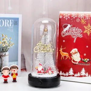 Cupola di vetro natalizia con albero bianco e Babbo Natale accanto a una scatola rossa