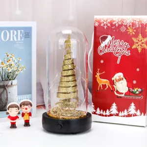 Dettaglio di un albero di Natale LED in cupola di vetro con confezione regalo festiva.