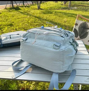 Detail of a light blue large capacity minimalist nylon backpack on a camping table