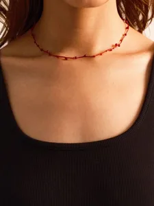 Close-up of hand-woven red cord necklace with dainty red agate beads on female model