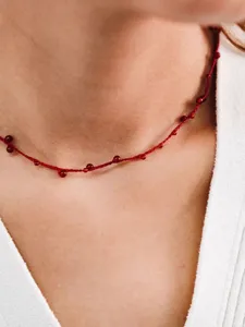 Macro view of hand-woven red string choker necklace featuring delicate red agate beads