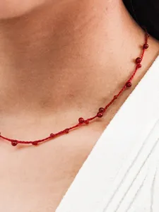 Detailed macro view of handmade red string necklace featuring small red agate beads
