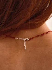 Close-up of silver lobster clasp and extension chain on a red cord necklace.