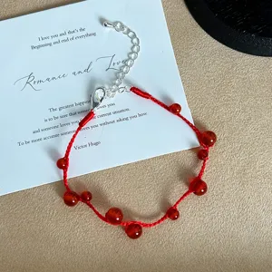 Detail of handmade red string bracelet with polished red agate beads and silver clasp