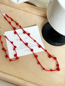 Close-up detail of hand-woven red agate beads on necklace and bracelet set jewelry.