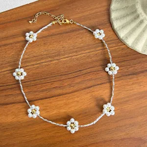 Close-up detail of pearl flower choker necklace with gold beads on wooden surface
