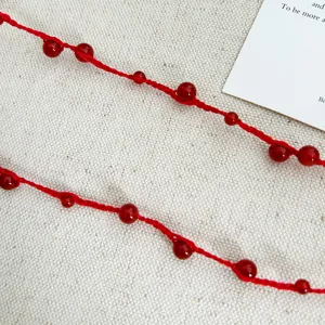 Close-up detail of hand-woven red cord necklace with polished carnelian beads