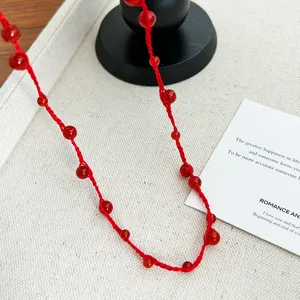 Detail shot of a handmade red woven rope necklace with polished red agate beads