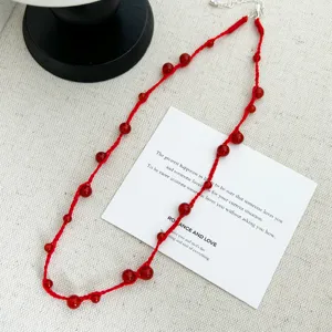 Close-up of red agate beaded necklace with handmade woven cord on a card