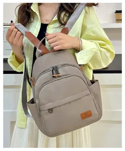Casual nylon backpack detail showing front zipper pockets and leather patch branding.