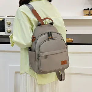 Casual minimalist women canvas backpack with brown leather accents and multiple zipper pockets.
