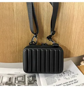 Primer plano del mini bolso maleta rígido negro mate con nervaduras.