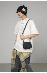 Modelo asiático con un mini bolso bandolera rígido negro estilo maleta de viaje