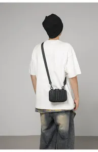 Vista trasera de un modelo con mini bolso bandolera rígido negro estilo maleta
