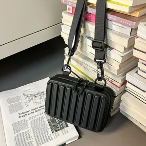 Bolso bandolera rígido negro con diseño de rayas verticales y estilo de maleta mini