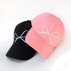 Detailaufnahme von süßen Baseballkappen mit Schleifenstickerei in Schwarz und Rosa.