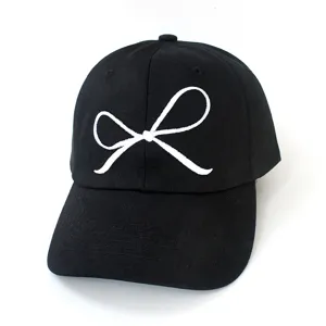 Nahaufnahme einer schwarzen Baseballkappe mit eleganter weißer Schleife Stickerei Detail.
