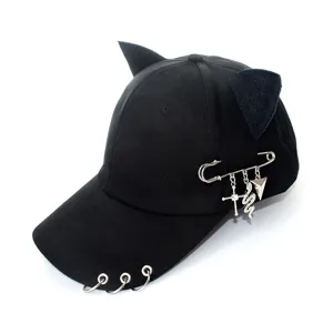 Black baseball cap detail showing punk style metal rings and chain pin accessories.