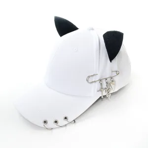 White baseball cap featuring black cat ears, metal rings, and gothic safety pin charms.