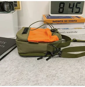 Primo piano di borsa a tracolla verde oliva con rete arancione e coulisse
