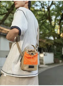 Piccola borsa a secchiello sportiva arancione e beige con coulisse indossata da modello