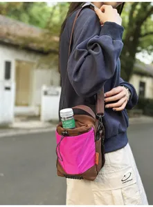 Primo piano di una borsa a secchiello a tracolla rosa e marrone indossata all'aperto.