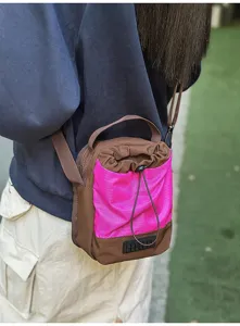 Vista dettagliata di una leggera borsa a tracolla marrone e rosa con coulisse indossata da modella