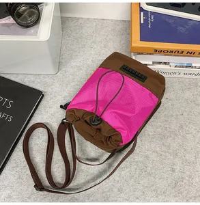 Dettaglio ravvicinato di una borsa a secchiello rosa e marrone con coulisse e chiusura.